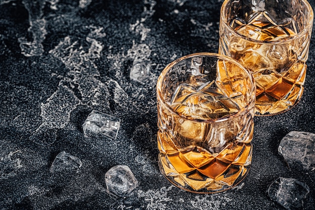 Whisky con ghiaccio su uno sfondo scuro di pietra.