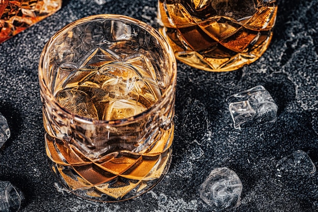 Whiskey with ice on a stone dark background.