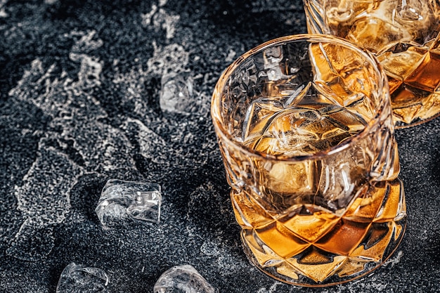 Whiskey with ice on a stone dark background.