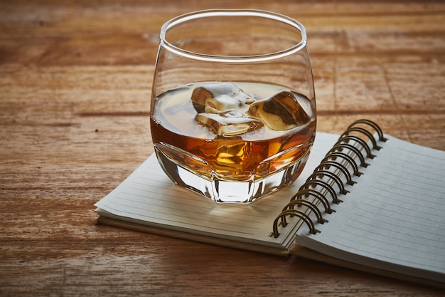 whiskey with note book on wooden table