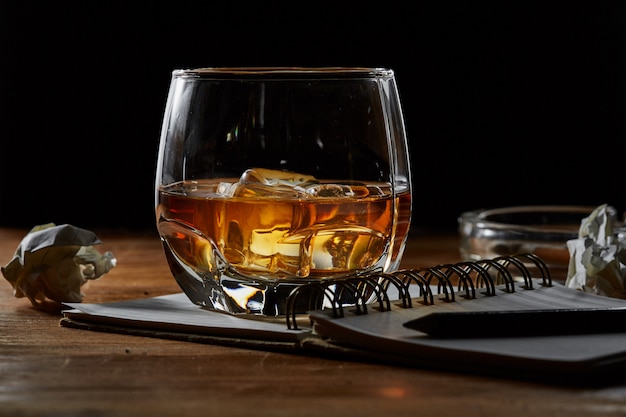 whiskey with note book on wooden table