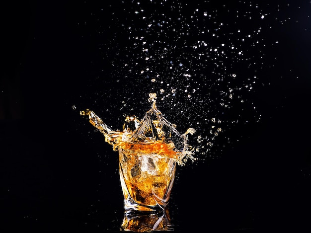 Whiskey with splash on black background brandy in a glass