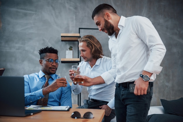 Whisky drinken. Groep multiraciale kantoormedewerkers in formele kleding praten over taken en plannen