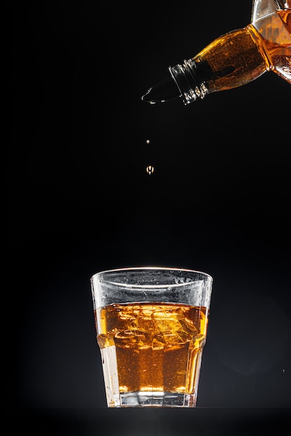 Whisky gieten in een glas op zwarte achtergrond