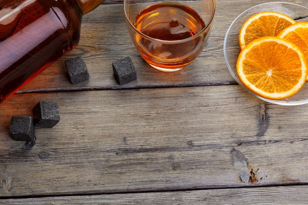 Whisky glass with orange fruit cut on dark wooden