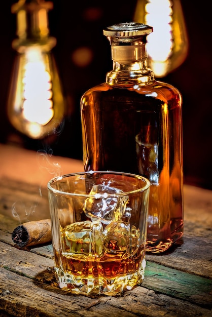 Whisky in fles en glas met sigaar op houten tafel