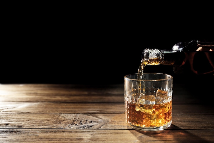 Foto whisky in glas gieten op houten tafel close-up