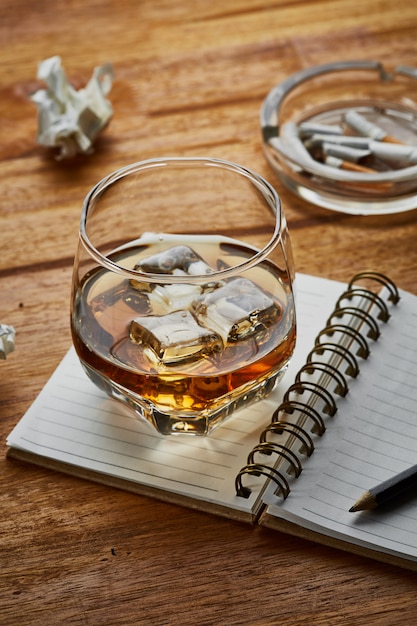 whisky met notitieboek op houten tafel