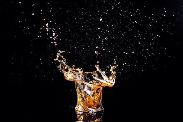 Whisky met plons op zwarte achtergrondbrandewijn in een glas
