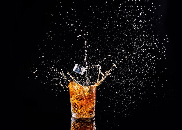 Whisky met splash op zwarte achtergrond, brandewijn in een glas