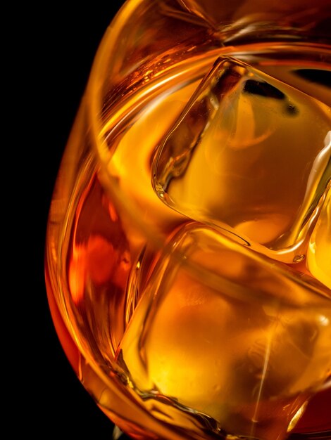 Whisky on the rocks glass filled with ice cubes closeup shot