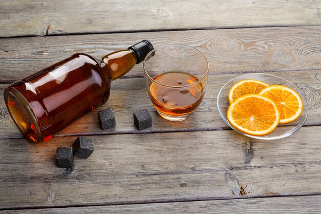 Whiskyglas met oranje fruit dat op donkere houten achtergrond wordt gesneden