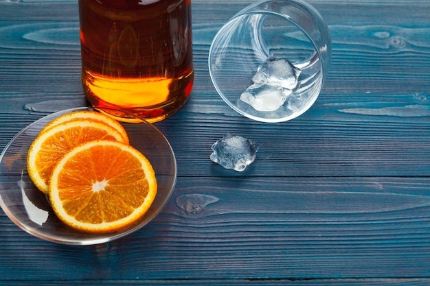 Whiskyglas met oranje fruit dat op donkere houten wordt gesneden