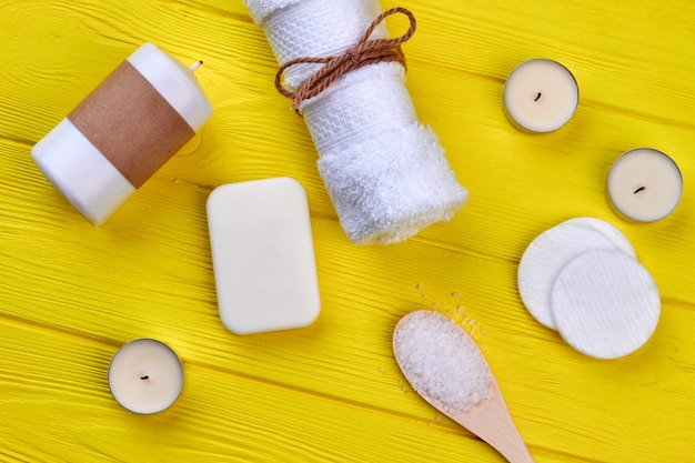 White accessories for spa on yellow wooden desk. Top view flat lay.