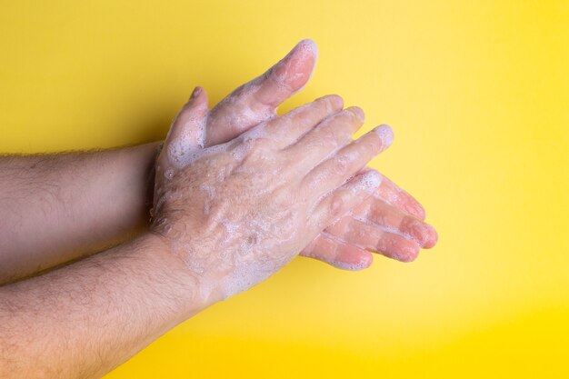 White adult man washing his hands with soap on the yellow