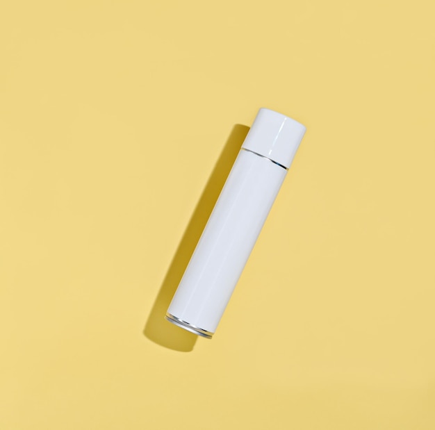 white aerosol spray bottle on a yellow background mock up for your design classic shaped tin can for home cleaning brands hair or disinfecting product