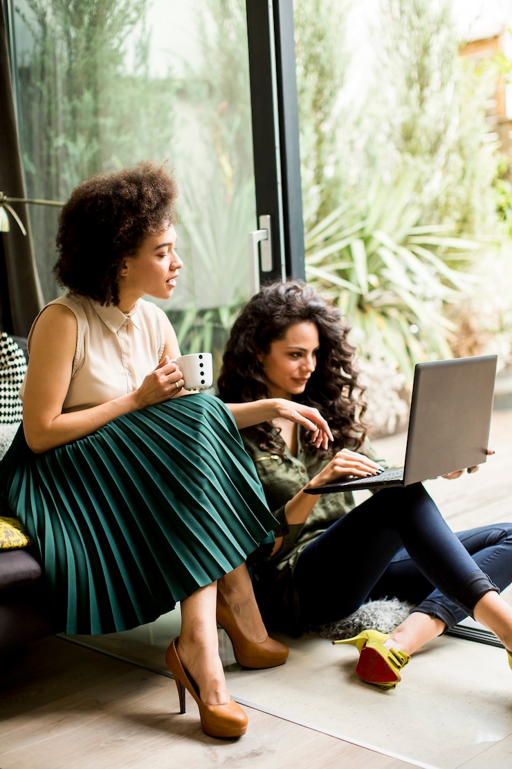Photo white and african american  women sit at home and using laptop