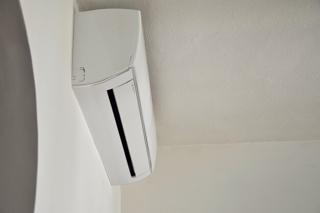 A white air conditioner is mounted on a white wall.