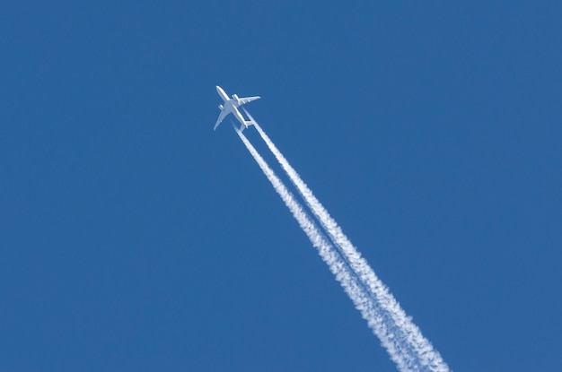 Белый самолет большой два двигателя авиации аэропорта инверсионные облака.