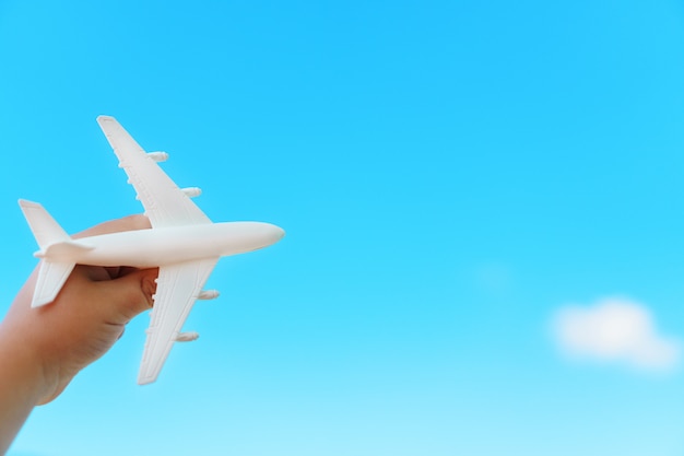 A white airplane in a child's hand against a blue sky.