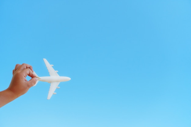 A white airplane in a child's hand on blue sky