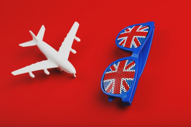 白い飛行機とイギリスの国旗とサングラス。イギリスへの旅行。