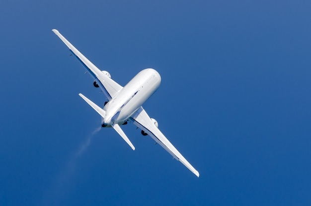 White airplane takes off in the rain in the blue sky.