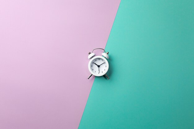 White alarm clock on colorful. Concept in minimal style