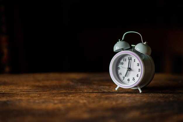 White alarm clock on a dark wooden background Place for text Circadian rhythm time management