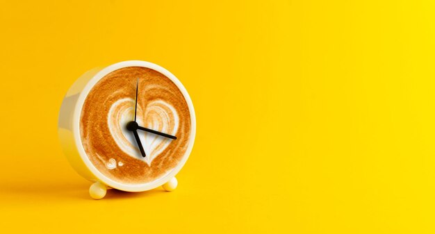 White alarm clock in front of hot coffee yellow background with empty space