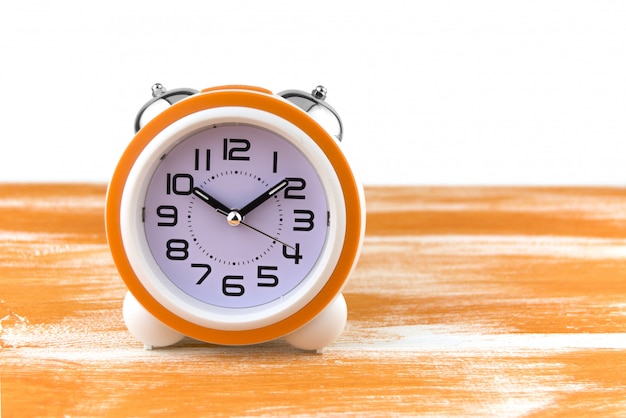 White alarm clock on a orange wooden table