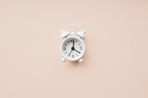 White alarm clock on a pink background with copy space