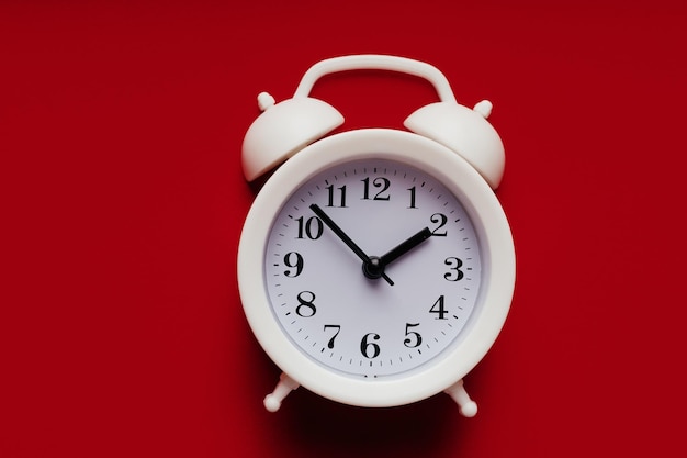 White alarm clock on a red background closeup