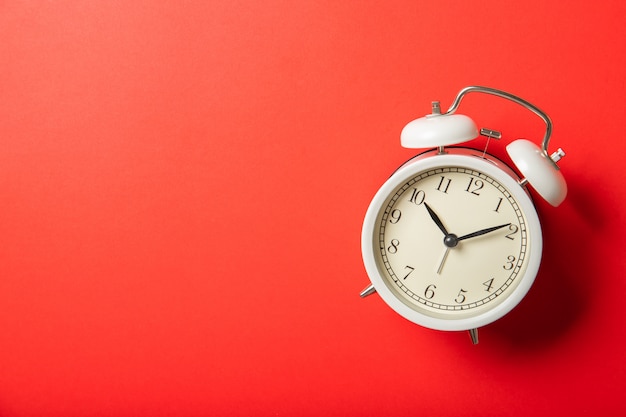 Photo white alarm clock on a red background