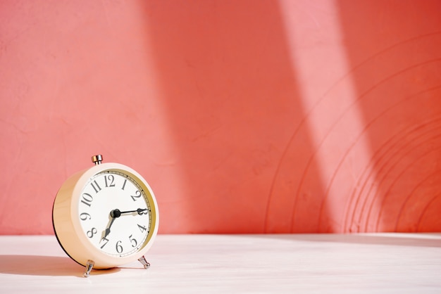 White alarm clock on the table against the orange wall