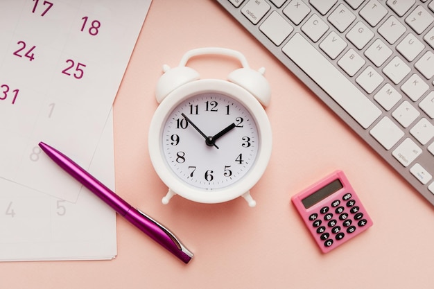 White alarm clock with sheets of calendar pen and keyboard closeup