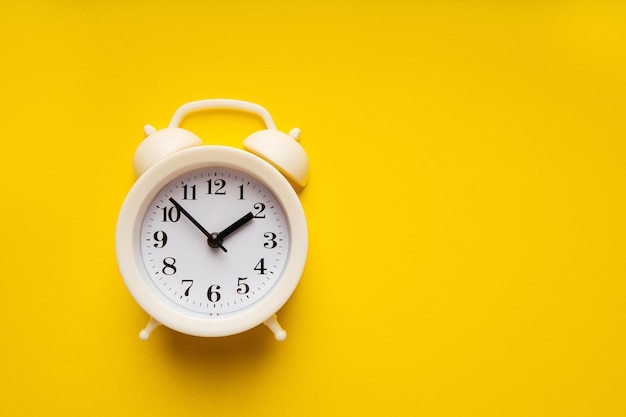 White alarm clock on a yellow background