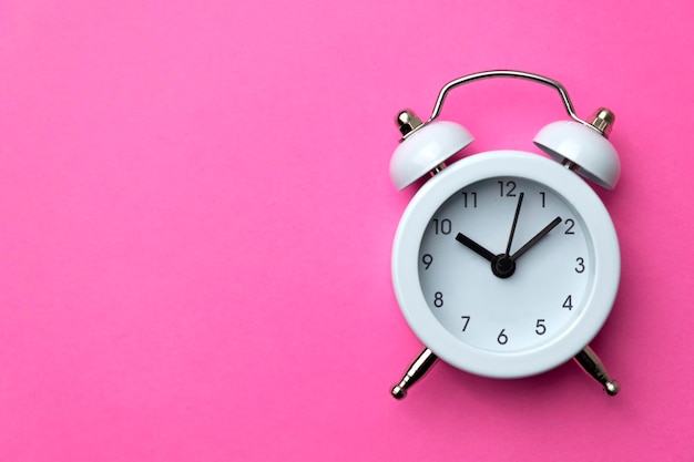 White analog alarm clock isolated on pink background Concept of time management Copy space