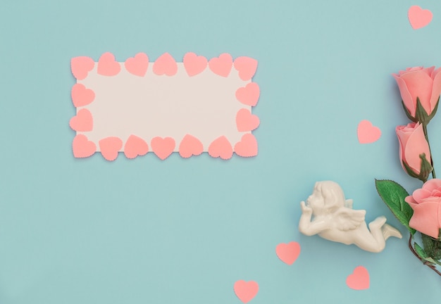 White angel, blank sheet with pink hearts frame and roses on blue