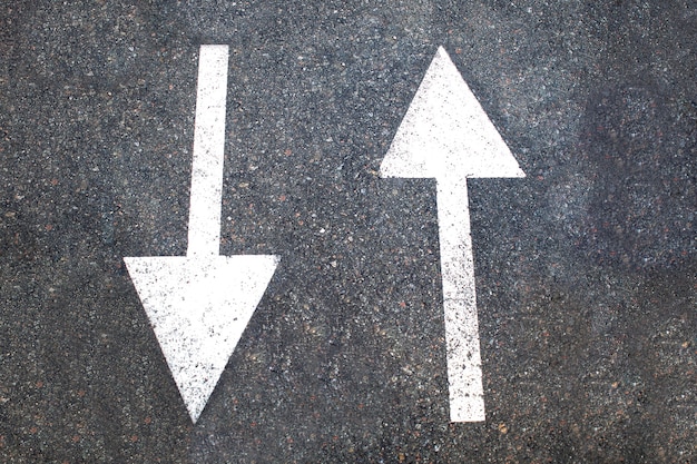 White arrow sign on asphalt road, top view