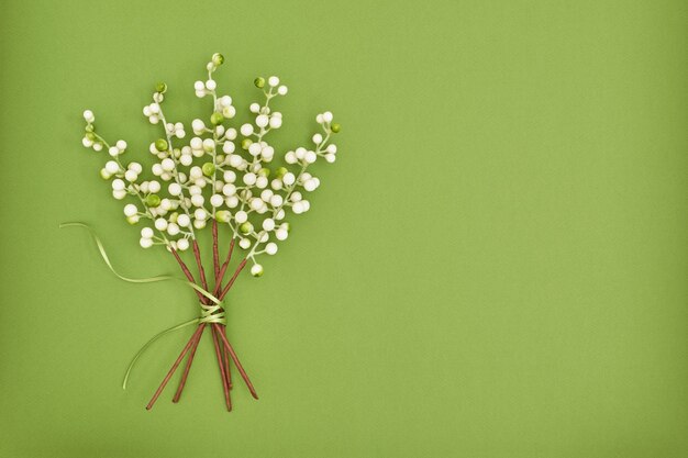 White artificial berries bouquet on green paper background