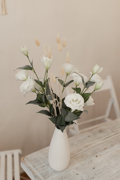 White artificial flowers in a vase. Decorative flowers on the table. Flowers in the interior.