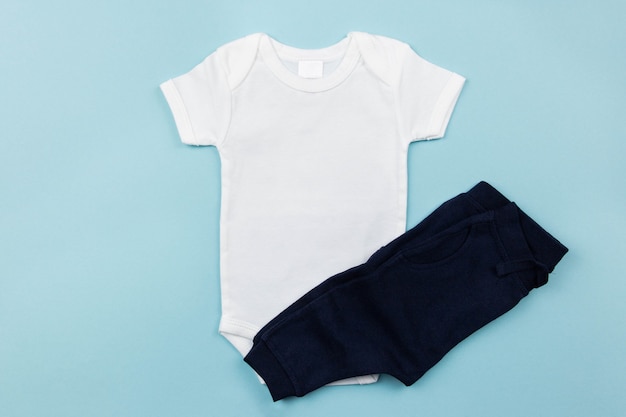 White baby boy bodysuit mockup flat lay with dark panties on the blue surface