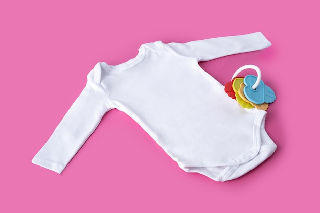 Vestiti bianchi per bambini e chiavi colorate su sfondo rosa