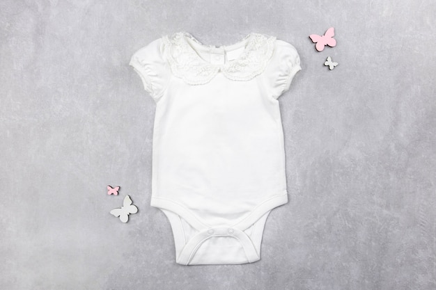 White baby girl bodysuit mockup flat lay on the gray concrete surface