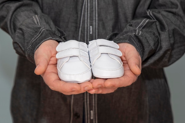 White baby shoes in father's hand