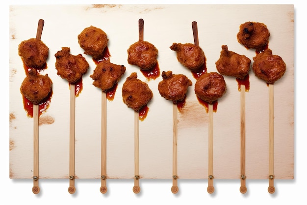 On a white background a board with delectable chicken lollipops