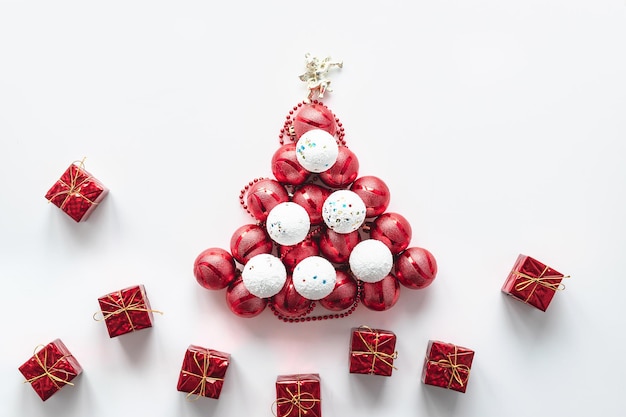 On a white background, a Christmas tree made of white and red balls with an angel and gifts. Festive postcard.