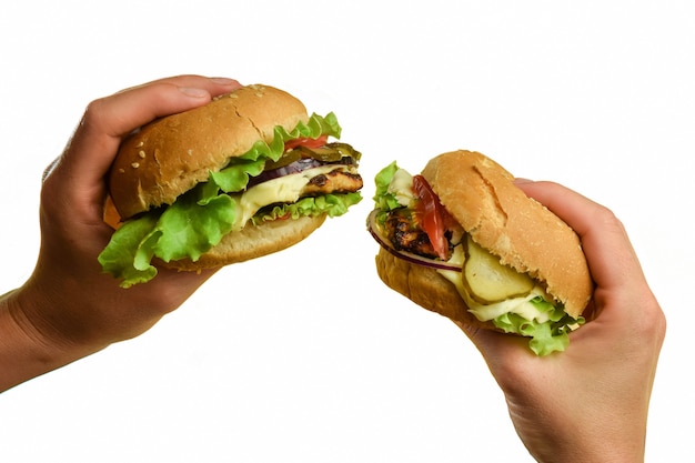 On a white background two sandwiches in each hand with meat, cheese, tomatoes, onions, cucumbers and salad