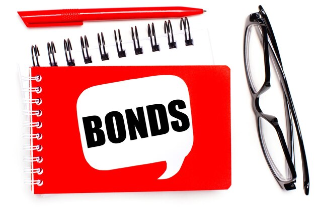 白地に白と赤のメモ帳、黒のメガネ、赤のペン、白のカードに「BONDS」というテキストが表示されます